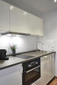 a kitchen with white cabinets and a sink at Airport & Messe Apartments in Hannover +14 photos