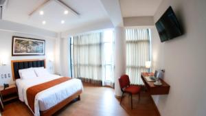 a hotel room with a bed and a desk and a television at Hotel Ottavis in Chiclayo