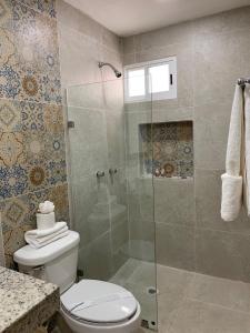 a bathroom with a toilet and a glass shower at Hotel Catedral Valladolid Yucatan in Valladolid