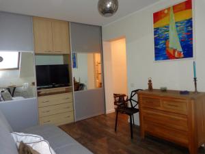 Apartamentai Dorė في نيدا: غرفة نوم مع سرير وخزانة مع تلفزيون