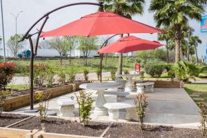 two red umbrellas over a table and benches at Merit Inn and Suites in Beaumont