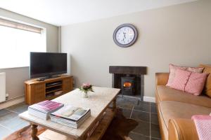 a living room with a couch and a tv and a fireplace at Grooms Cottage in Weedon Bec