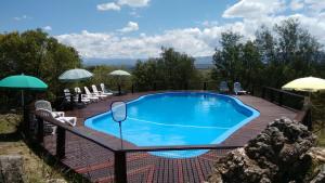 uma piscina num deque com cadeiras e guarda-sóis em Vista del Condor em Villa Ciudad de America