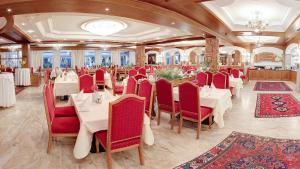 Hotel Purner في Thaur: مطعم بطاولات بيضاء وكراسي حمراء