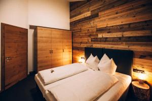 ein Schlafzimmer mit einem Bett mit einer Holzwand in der Unterkunft Riefli Aparts in Sankt Anton am Arlberg