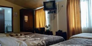 Habitación con 2 camas y TV en la pared. en Hostal El Roble, en Quito