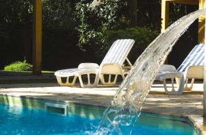 a pool with two lawn chairs and a fountain at Condomínio Boiçucanga in Boicucanga +2 photos