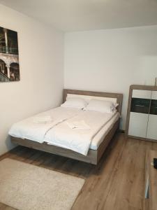 1 dormitorio con 1 cama con sábanas blancas y espejo en Focus Home en Miercurea-Ciuc