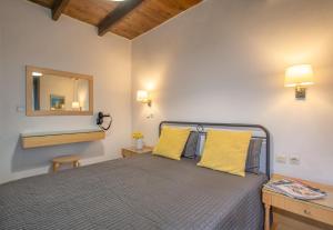 1 dormitorio con cama con almohadas amarillas y espejo en Nancy - Chara Apartments, en Karteros