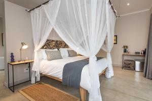 um quarto com uma cama de dossel com cortinas brancas em Nyaleti Lodge em Hoedspruit