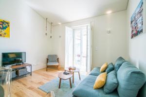 a living room with a blue couch and a tv at Liberdade Apartment in Lisbon
