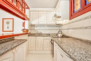 a kitchen with white cabinets and granite counter tops at Parque Santiago IV in Playa de las Americas