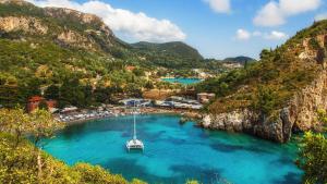 a boat in a body of water next to a mountain at Alsos Family Apartment in Corfu