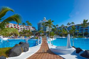 a resort swimming pool with a boat in the water at Parque Santiago IV Official in Playa de las Americas