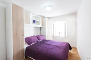 Holiday Home Revelin- Great Location في دوبروفنيك: غرفة نوم مع سرير مع ملاءات أرجوانية ونافذة