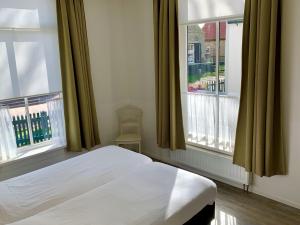 - une chambre avec un lit blanc et 2 fenêtres dans l'établissement De Eerste Stuiver, à Hollum