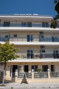 a large white building with balconies and a tree at Olympic Coast in Olympic Beach