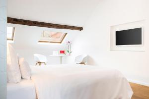 a white bedroom with a white bed and a tv at B&B X2Brussels in Brussels