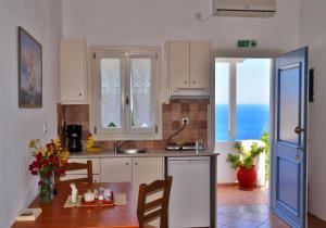 a kitchen with white cabinets and a table with chairs at Lefkanthemo in Astypalaia