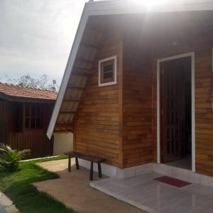 a wooden house with a bench in front of it at Chalé Flor Da Serra in São José do Barreiro