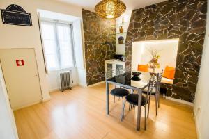 ein Esszimmer mit einem Tisch und einer Steinmauer in der Unterkunft Apartment São Lourenço in Lissabon