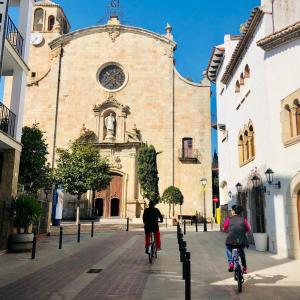 zwei Personen, die vor einer Kirche Fahrrad fahren in der Unterkunft Charming loft - Historical Center in Tossa de Mar