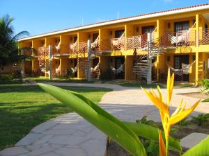 a yellow building with a palm tree in front of it at Hotel Aconchego Porto de Galinhas in Porto De Galinhas