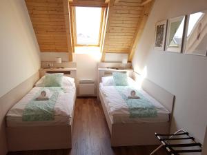 two beds in a small room with two windows at Apartmán NIKI Apollon Resort Lednice in Lednice