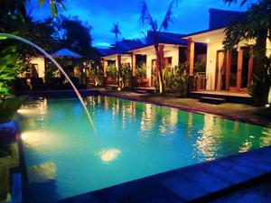 a swimming pool with a fountain in front of a house at Singabu Bungalows in Nusa Penida