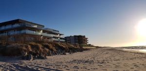 a building on the beach with footprints in the sand at Apartament MORSKI WIDOK GARDENIA Dziwnów in Dziwnów