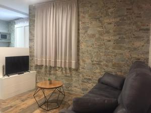 a living room with a couch and a stone wall at Ático del Rojas in Toledo
