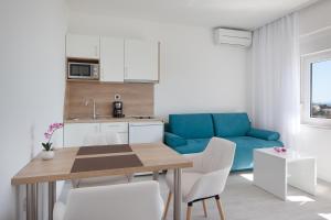 uma cozinha e sala de estar com uma mesa e um sofá azul em Villa King Apartments em Brela