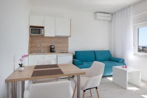 een keuken en een woonkamer met een tafel en een blauwe bank bij Villa King Apartments in Brela