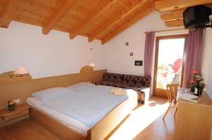 - une chambre avec un grand lit et une grande fenêtre dans l'établissement Der Brunnerhof, à Rio di Pusteria
