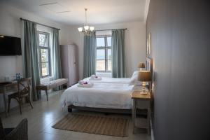 a bedroom with a white bed and a desk and window at Casa al Mare Guest House in Swakopmund