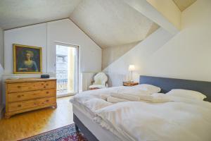a large white bedroom with a large bed and a dresser at Duplex de charme au cœur de la vieille ville de Sion in Sion