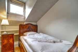 a bedroom with a bed with a wooden headboard and a window at Duplex de charme au cœur de la vieille ville de Sion in Sion
