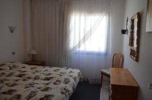 a bedroom with a bed and a table and a window at Los Angeles in Los Cristianos