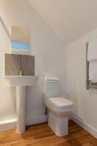 uma casa de banho com um WC branco e um lavatório. em Charlie Mews em Farnborough