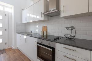 a kitchen with white cabinets and a black counter top at Charlie Mews in Farnborough