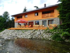 a house with tables and chairs next to a river at Apartmány Limba in Demanovska Dolina