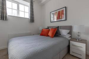 a bedroom with a bed with orange pillows on it at Charlie Mews in Farnborough