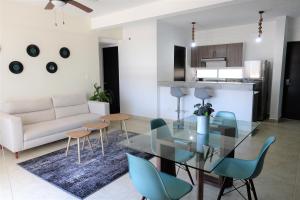 ein Wohnzimmer mit einem Glastisch und blauen Stühlen in der Unterkunft Ideal tu casa fuera de casa in Cancún