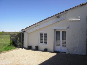 un bâtiment blanc avec une porte dans un champ dans l'établissement La Petite Grange gîte climatisé plain-pied 3 chambres 5 personnes 2 toilettes parking WIFI piscine d'été chauffée animaux acceptés Gîte en pleine nature, à Lorignac 26 autres photos