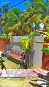 a bench in a yard with palm trees at Corvina Suites in Praia do Forte