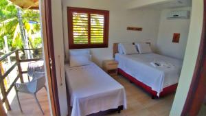 a bedroom with a bed and a balcony at Corvina Suites in Praia do Forte