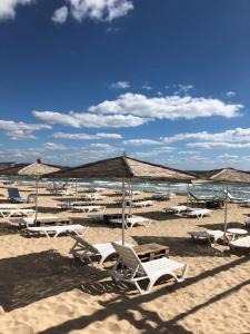 a group of chairs and umbrellas on a beach at Summer Breeze Villa in Balchik