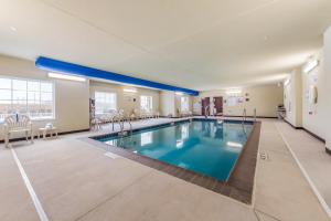 uma grande piscina num quarto de hotel com cadeiras e mesas em Cobblestone Hotel & Suites - Hutchinson em Hutchinson