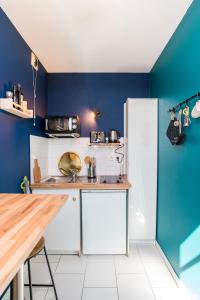 a kitchen with blue walls and a white refrigerator at Le Paon - Netflix - Plein centre in Toulouse