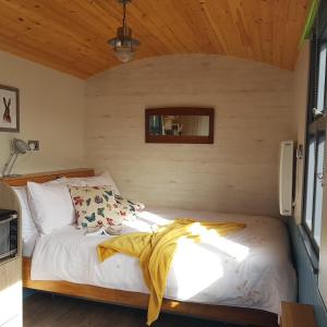 Cama en habitación pequeña con techo de madera en Dingle Way Glamping, en Anascaul